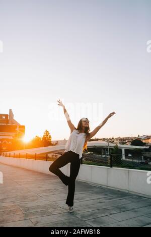 Portrait carefree young female dancer on sunny urban sidewalk Stock Photo