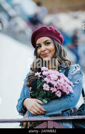 Portrait smiling young woman in beret holding flower bouquet Stock Photo