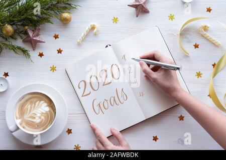 Woman writing in notebook goals plans wish list for new year 2020, flat lay Stock Photo