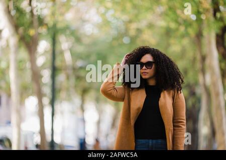 Stylish young woman in sunglasses walking in park Stock Photo