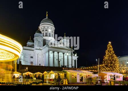 Christmas market on Senate Square in Helsinki, Finland. Cathedral, tree and spinning carousel at night Stock Photo