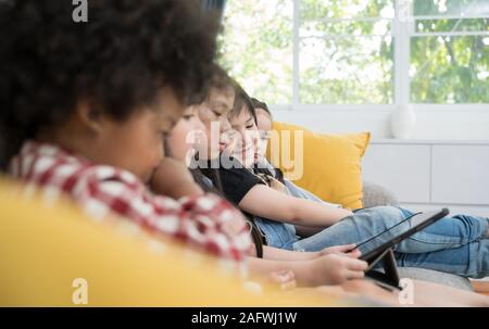 group of little children watching film movie cartoon together on digital tablet. Kids playing with tablet with friends at home Stock Photo