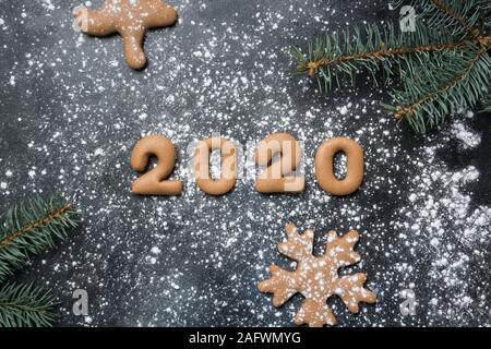 Christmas gingerbread cookie in date 2020 Year on black snowy surface. View from above Stock Photo