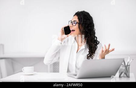 Mexican woman talking on cell phone at office Stock Photo