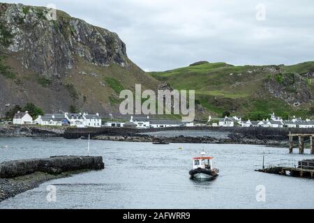 Looking back towards the harbour of Ellenabeich, a small village on the isle of Seil  from Easdale Island with the small ferry boat approaching Stock Photo