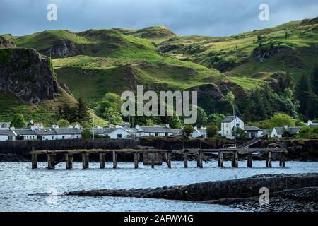 Looking back towards the harbour of Ellenabeich, a small village on the isle of Seil  from Easdale Island showing the old slate jetty. Stock Photo