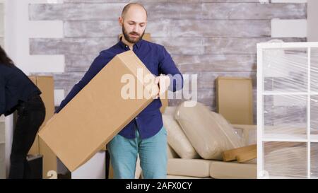 Caucasian young couple moving in their new home. Professional movers delivering cardboard boxes to door. Stock Photo