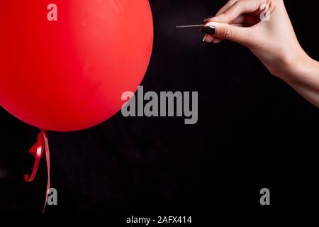 burst red balloon with a needle - danger concept Stock Photo