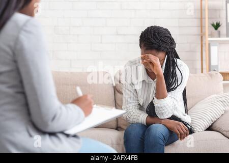 Depressed woman sitting on couch at psychotherapy session in coucellor's office Stock Photo
