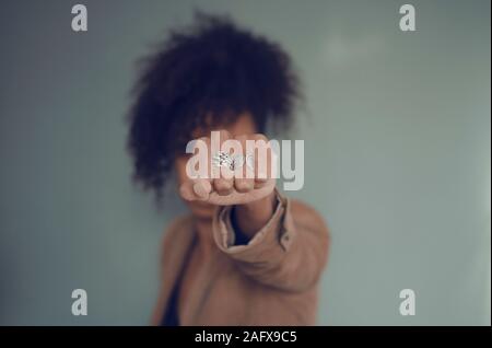 Closeup and selective focus on a black woman fist (with rings). Afro puff hair. Stock Photo