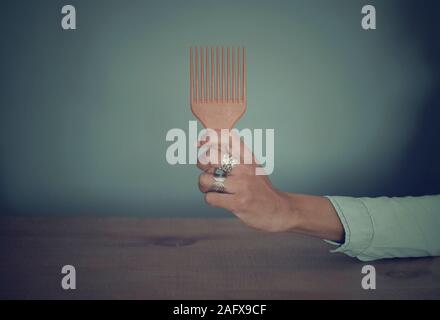 Selective focus on the hand (with rings) of a black woman holding an afro comb Stock Photo
