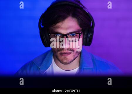 Programmer in headphones coding, working on computer Stock Photo