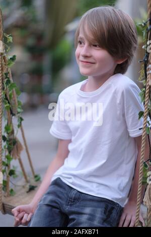 Portrait of a smiling boy sitting on a swing in the pavilion Stock Photo