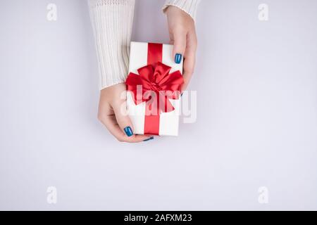 Beautiful gift box with red bow in female hands on Beautiful gift box with red bow in female hands on red background Stock Photo