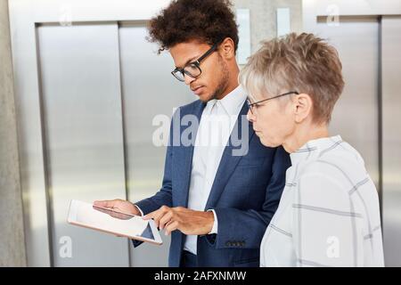 Young african businessman using tablet computer and senior colleague Stock Photo