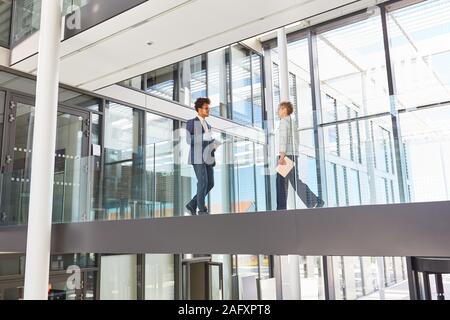 Two business colleagues walk through a gallery in the modern corporate headquarters Stock Photo