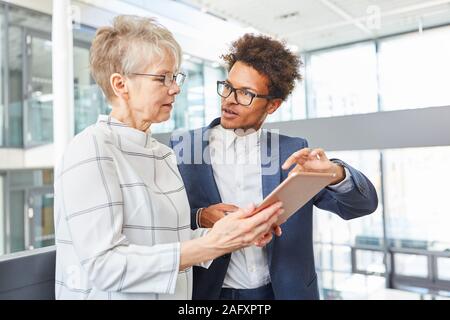 Software developer explains the new website design on the tablet to his boss Stock Photo