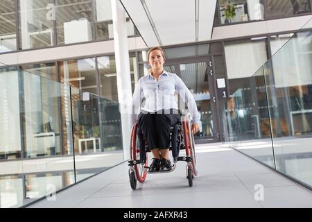 Woman as a wheelchair user on the move in the barrier-free office for inclusion concept Stock Photo
