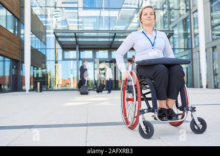 Businesswoman in a wheelchair in front of the office looks forward to conference on inclusion Stock Photo