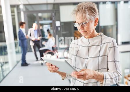Senior woman as boss using tablet computer online in business company Stock Photo