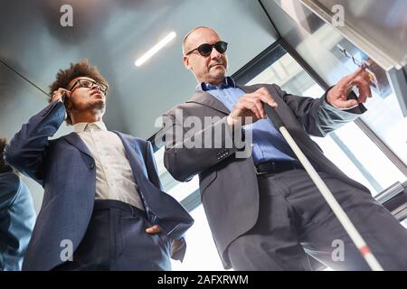 Blind man presses button in the elevator from the office Stock Photo
