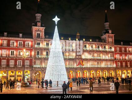 Plaza Mayor square at nightfall illuminated by a shinny christmas tree with the principal facade of The Casa de la Panaderia in the background. Madrid Stock Photo