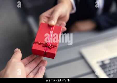 Business boss giving present gift box to office staff partner for job bonus concept. Stock Photo