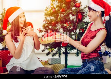 Asian woman giving Christmas new year gift box present to her friend feeling surprise expression. Stock Photo