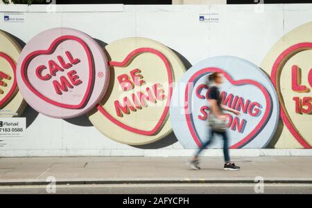 Love Hearts: Be Mine. Motion blurred pedestrian walking by advertising hoarding for Love Hearts, a popular UK sweet brand. Stock Photo