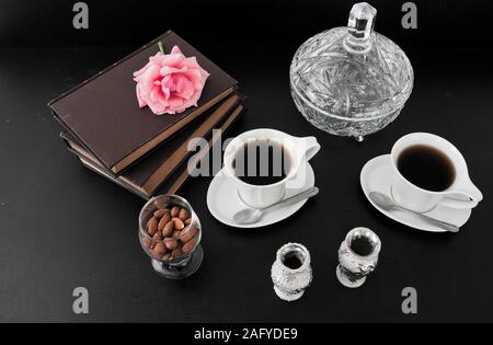 Tea items, books and a rose over a black surface Stock Photo