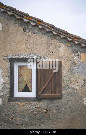 A tiny window with a flowery curtain in an old French house Stock Photo