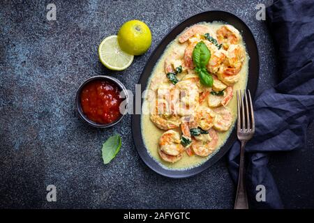 Shrimps in cream sauce with Coconut milk on a plate over black background, top view or view from above, flat lay Stock Photo