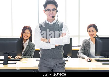 Portrait of Young adult friendly and confidence operator man with headsets and his team working in a call center as customer service and technical sup Stock Photo