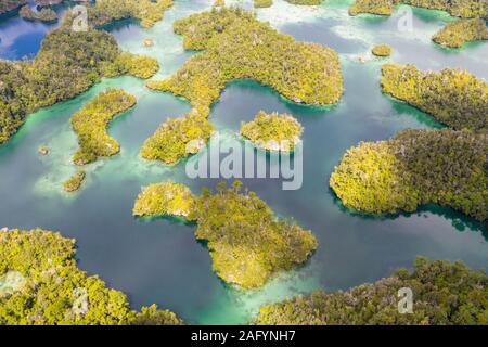 Highly eroded limestone islands and coral reefs lie amid the waters of Raja Ampat, Indonesia. This region is a popular destination for scuba divers. Stock Photo