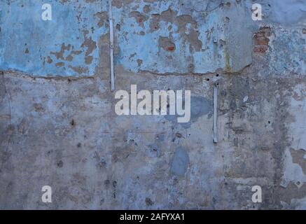Vintage neglected cement wall, the blue color is faded, part of the wall is cracked Stock Photo