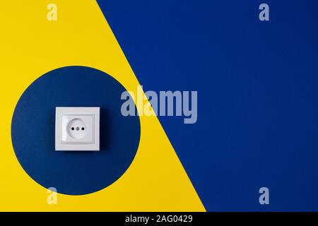 White electrical socket on geometric yellow and blue navy color background Stock Photo