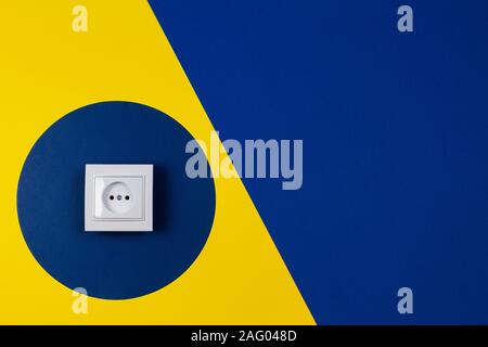 White electrical socket on geometric yellow and blue navy color background Stock Photo