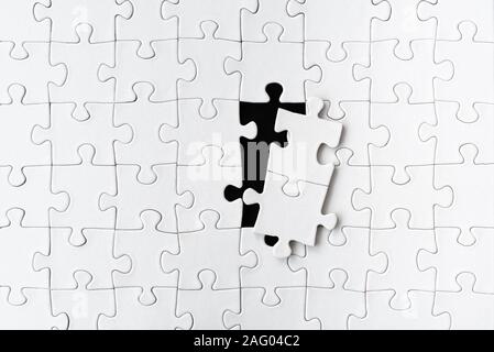 white blank jigsaw puzzle with two puzzle pieces taken out Stock Photo