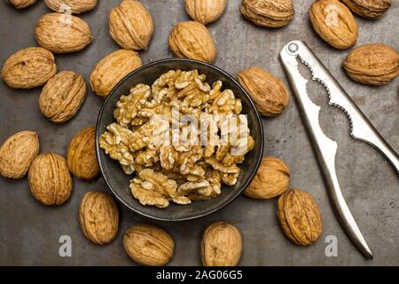 Walnuts kernels in a black bowl and walnuts on a metal table Stock Photo