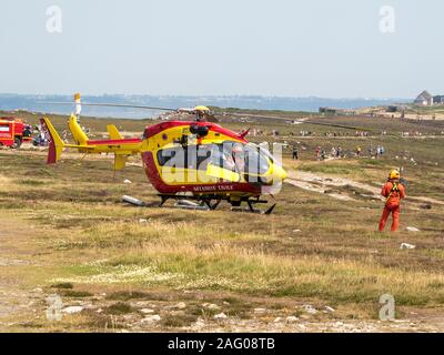 Civil security helicopter landed. One crew member in the cabin and the other standing in front of the aircraft. France Stock Photo