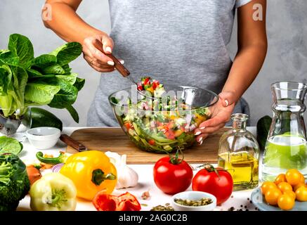 Woman holds a glass bowl full of vegetable salad and a spoon with it in her hand. Healthy vegan food, clean eating, dieting. Stock Photo