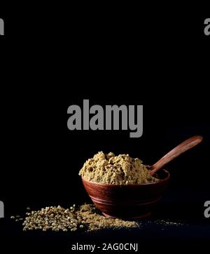 Coriander Powder in wooden bowl with seeds on black background Stock Photo