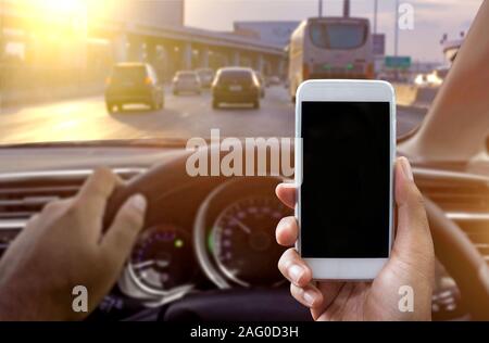 Man using a smartphone while driving a car - Sunset filter effect Stock Photo