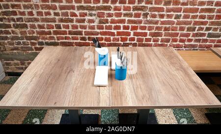 Nice rustic wooden table with set of asian setting against red brick wall Stock Photo