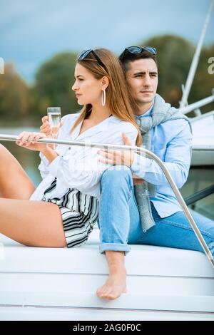 Couple celebrating with champagne on a boat .Attractive man uncorking champagne and having party with girlfriend on vacation.Two young tourists having Stock Photo