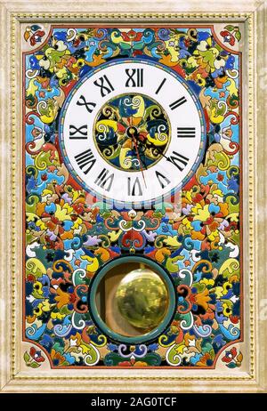 Ceramic clock with bright patterns in a wooden frame. Stock Photo