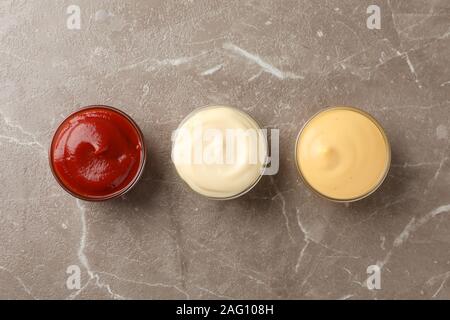 Tasty sauces in bowls on grey background, space for text Stock Photo