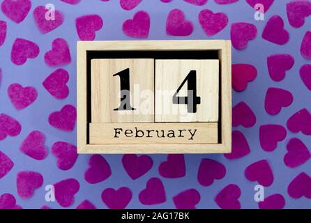 Wooden calendar cube show of February 14 on background with red hearts. Stock Photo