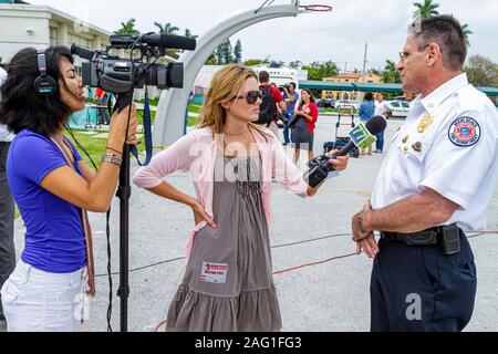 Miami Beach Florida,High School,DUI drinking driving simulated automobile accident,city TV cable reporter interviewing fire department chief Stock Photo