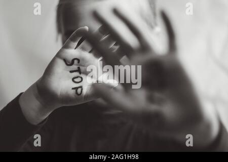 Little frightened girl shows the word Stop written on the arm. Children are subjected to violence and publishing in the home and school concept and Stock Photo